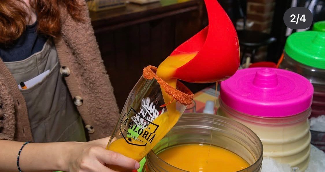 Servicio de bebida anaranjada con cucharón rojo sobre vaso escarchado en Cantina Masiosare, Coyoacán