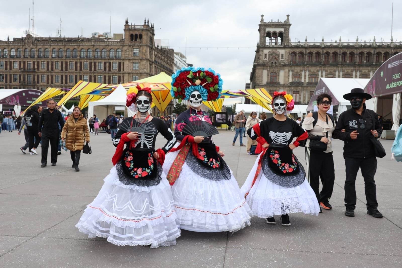 Tres catrinas maquilladas ante Palacio Nacional en el Zócalo de Ciudad de México
