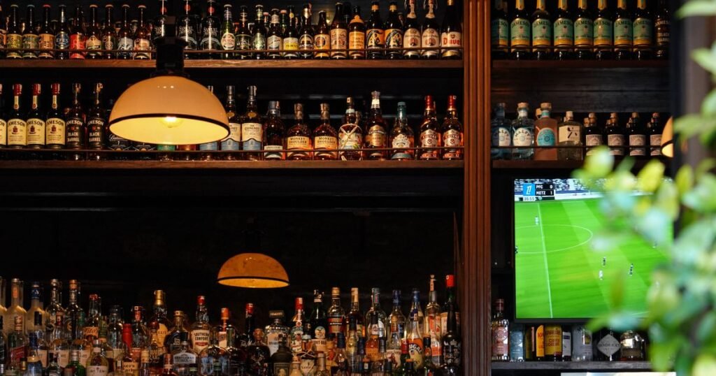 Interior de un bar con botellas y una pantalla