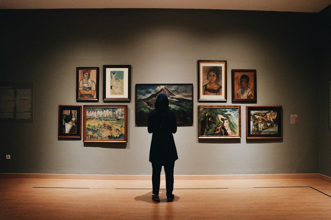 Visitante ante pinturas en una galería; fotografía ilustrativa de Zalfa Imani, Unsplash.
